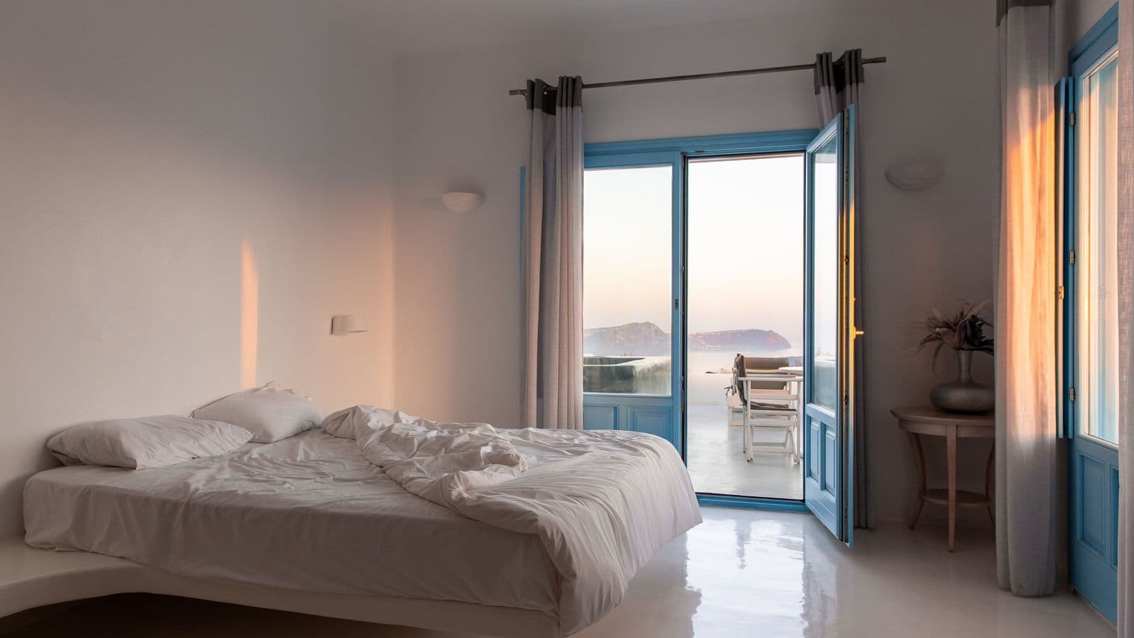 Empty hotel room with the balcony door open to a sea view