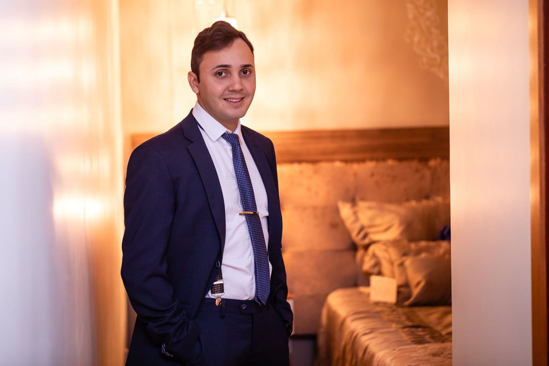 A smiling hotel manager in a suit in one of the hotel's rooms