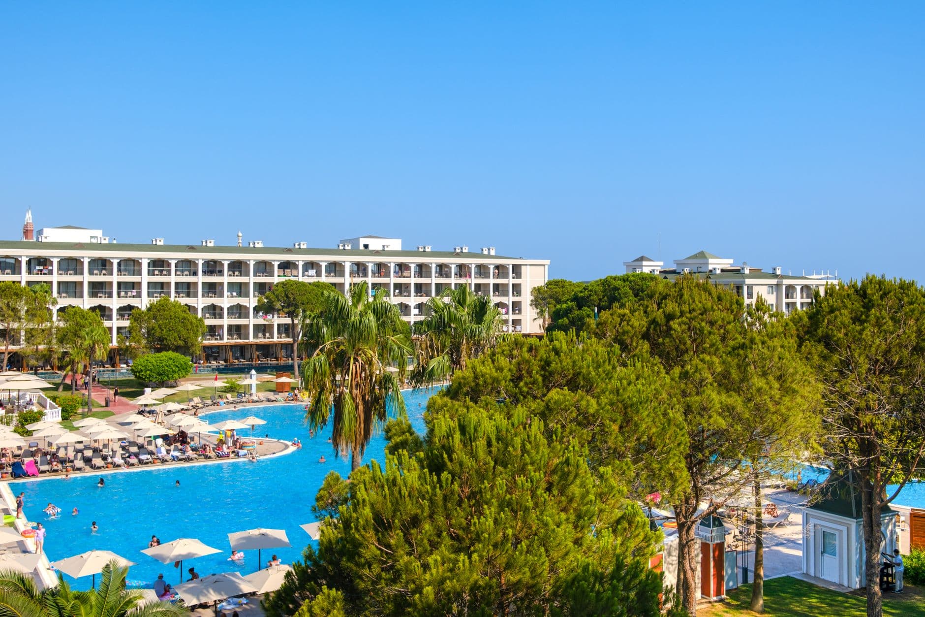 A Mediterranean resort hotel with a large pool and palm trees