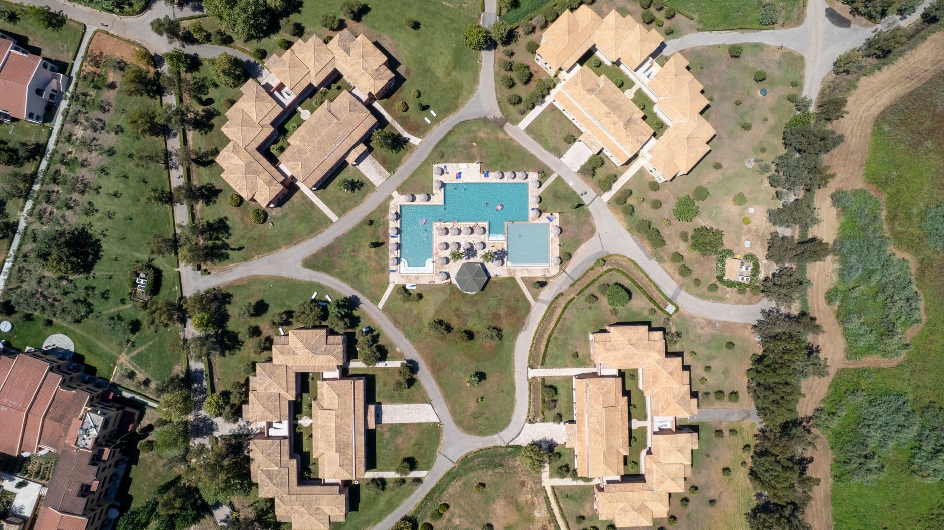 Aerial view of a resort with several guest buildings around a pool